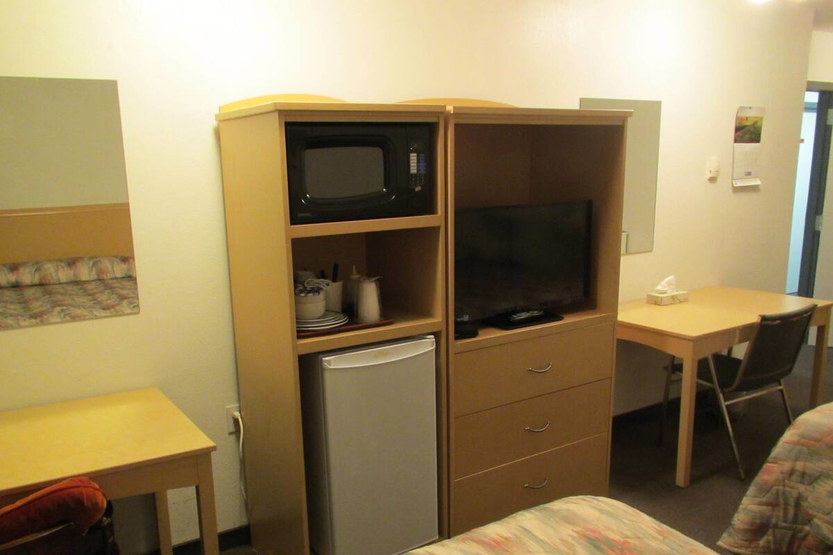 Habitación de hotel compacta con kitchenette, que incluye microondas, refrigerador y televisor pequeño.
