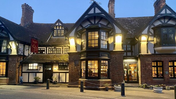 A traditional Tudor-style building with multiple windows and a thatched roof. - The Talbot (Blandford Forum)