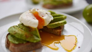 A plate with a poached egg, avocado slices, and toast, with a sauce on the plate. - The Talbot (Blandford Forum)