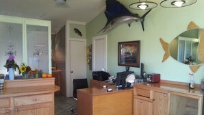 A kitchen with wooden cabinets, a dining table, a ceiling fan, and a fish decoration on the wall. - Windsor Motel (Lake George)
