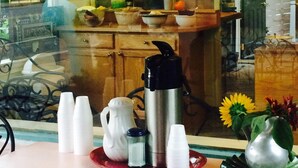A kitchen with wooden cabinets, a stainless steel kettle, salt and pepper shakers, and a red tray with white cups. - Windsor Motel (Lake George)