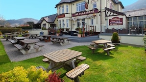 A building named "The Gladstone" with outdoor seating and picnic tables. - The Gladstone (Penmaenmawr)