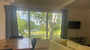 Ein Zimmer mit Esstisch, Stühlen, einer Couch und einem Fernseher.