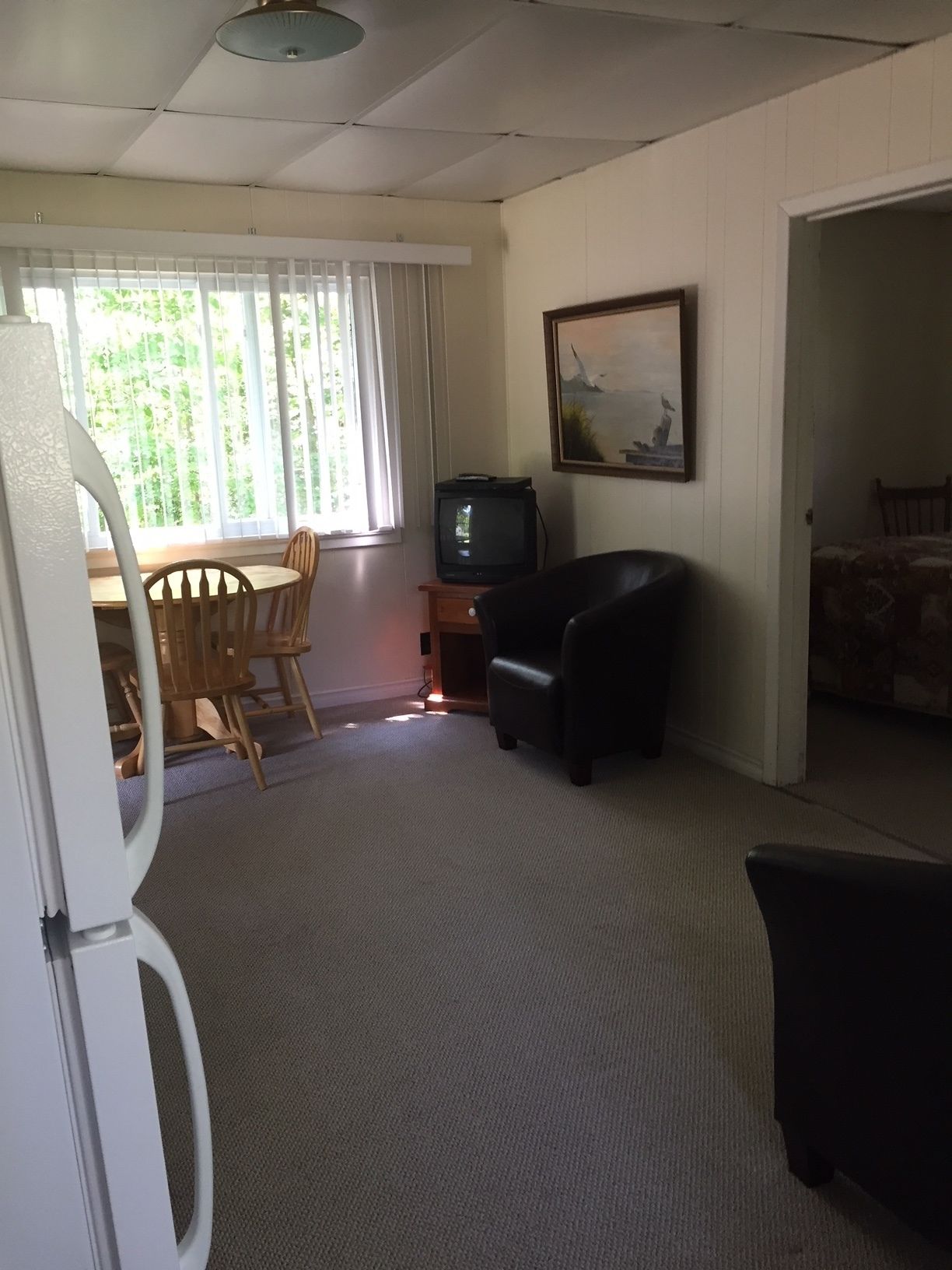 Ein Zimmer mit Esstisch, Stühlen, einem Fernseher und einem Gemälde an der Wand.