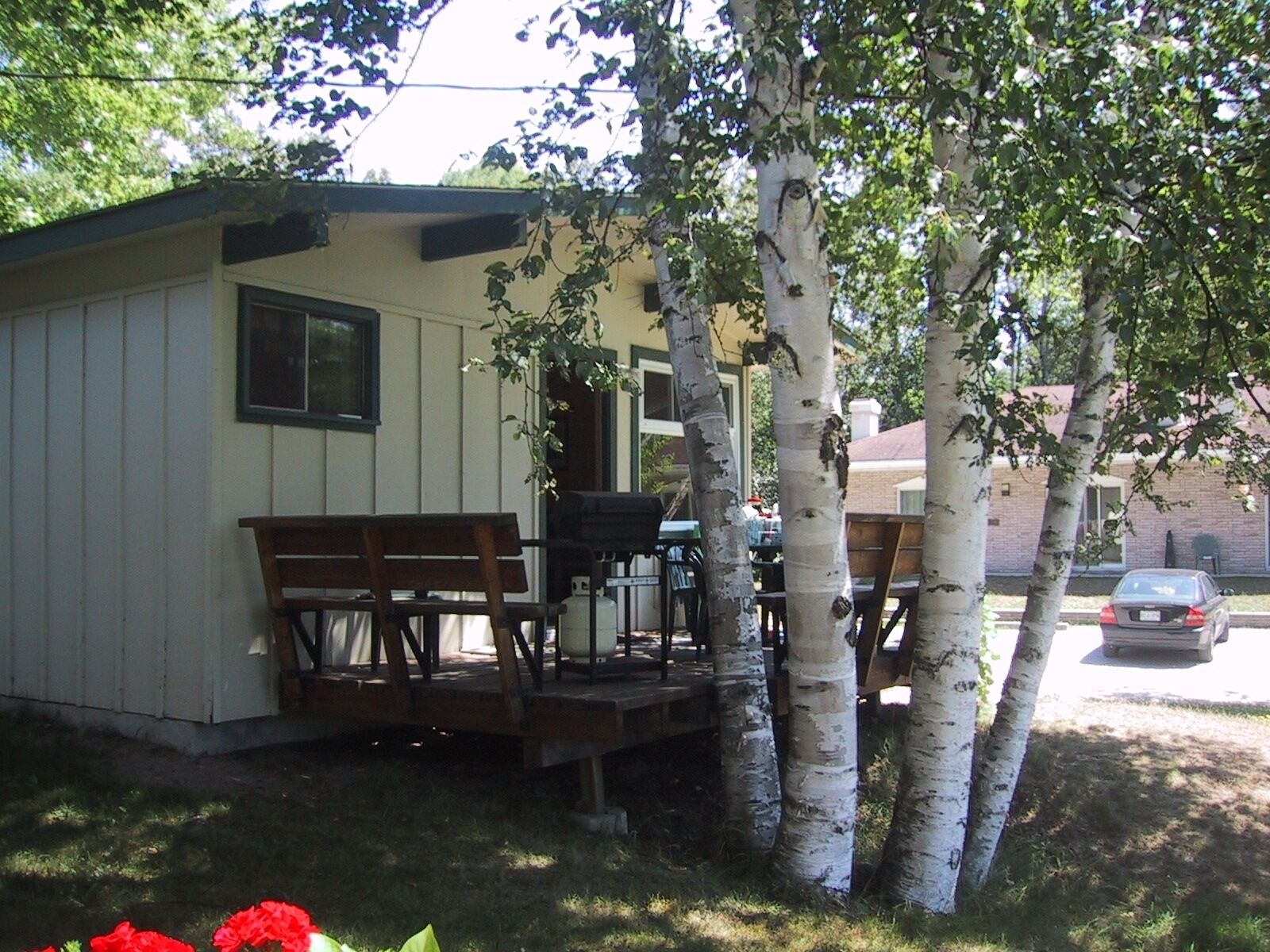 A small cabin with a porch, a table, and chairs.