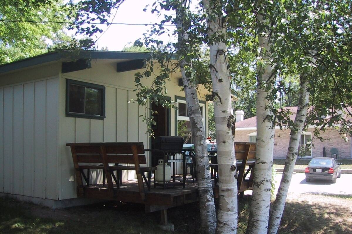 A small cabin with a porch, a table, and chairs.