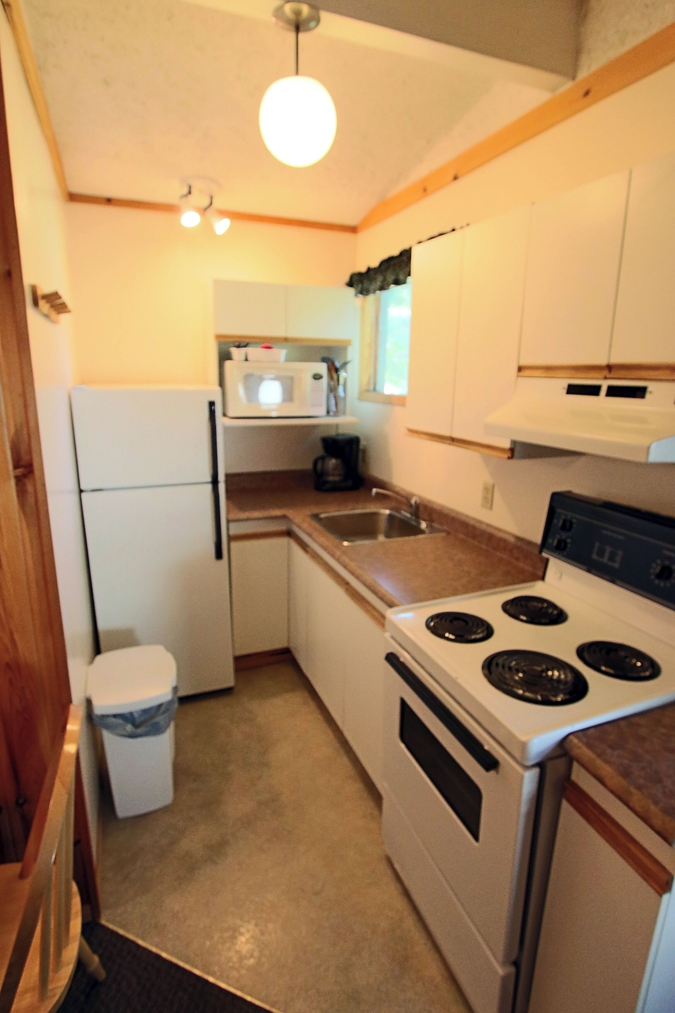 A compact kitchen with a stove, microwave, and sink.