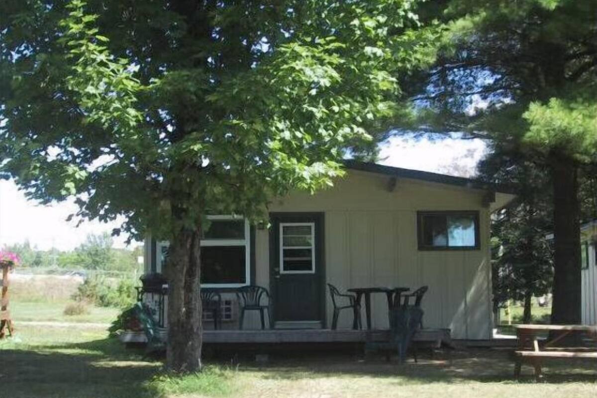 A single-story house with a porch, a small table, and a bench.