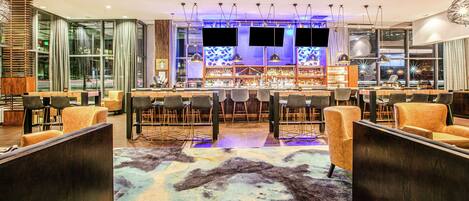 A modern bar area with seating, a bar counter, and a large window.