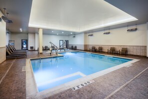An indoor swimming pool with a clear water depth marking, a sunlit ceiling, and a tiled floor.