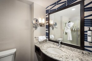 A bathroom with a marble sink, two wall-mounted mirrors, a large mirror, and a towel rack with white towels.