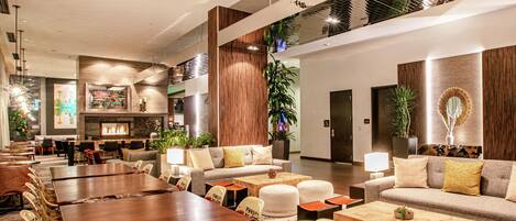 A spacious lobby with a high ceiling, multiple seating areas, and a variety of plants.