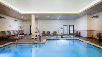 Una piscina con sillones de descanso y un vestuario.