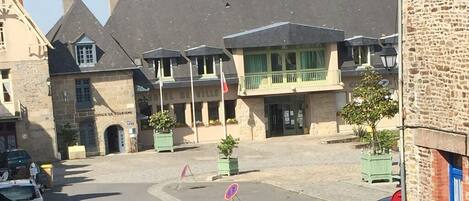 Une vue de rue avec un bâtiment portant l’inscription « Office de tourisme » et une voiture garée sur le bord.