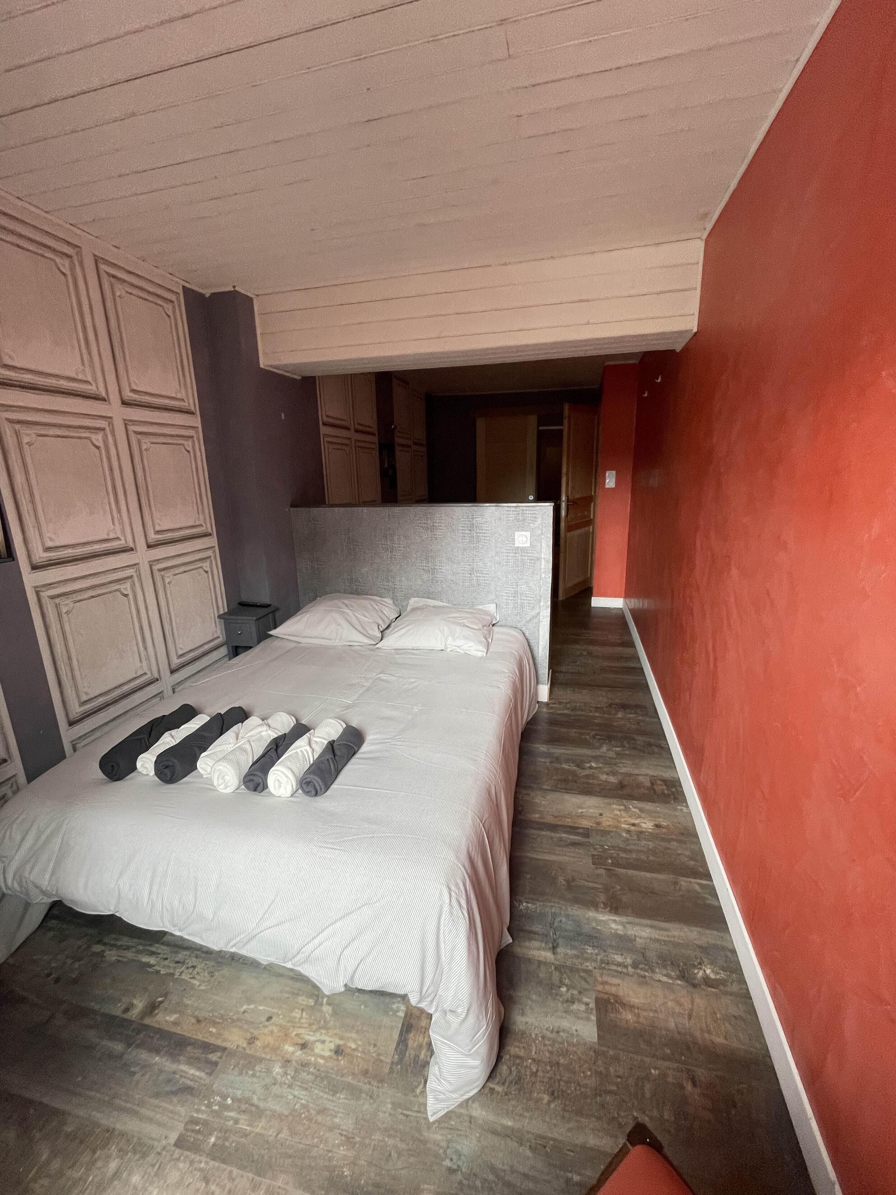 Ein Schlafzimmer mit einem Bett, Holzboden und einer roten Akzentwand.