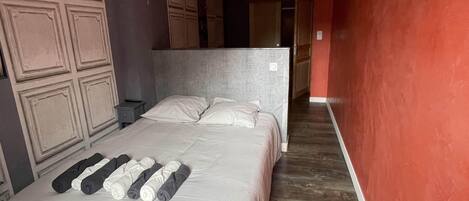 Ein Schlafzimmer mit einem Bett, Holzboden und einer roten Akzentwand.