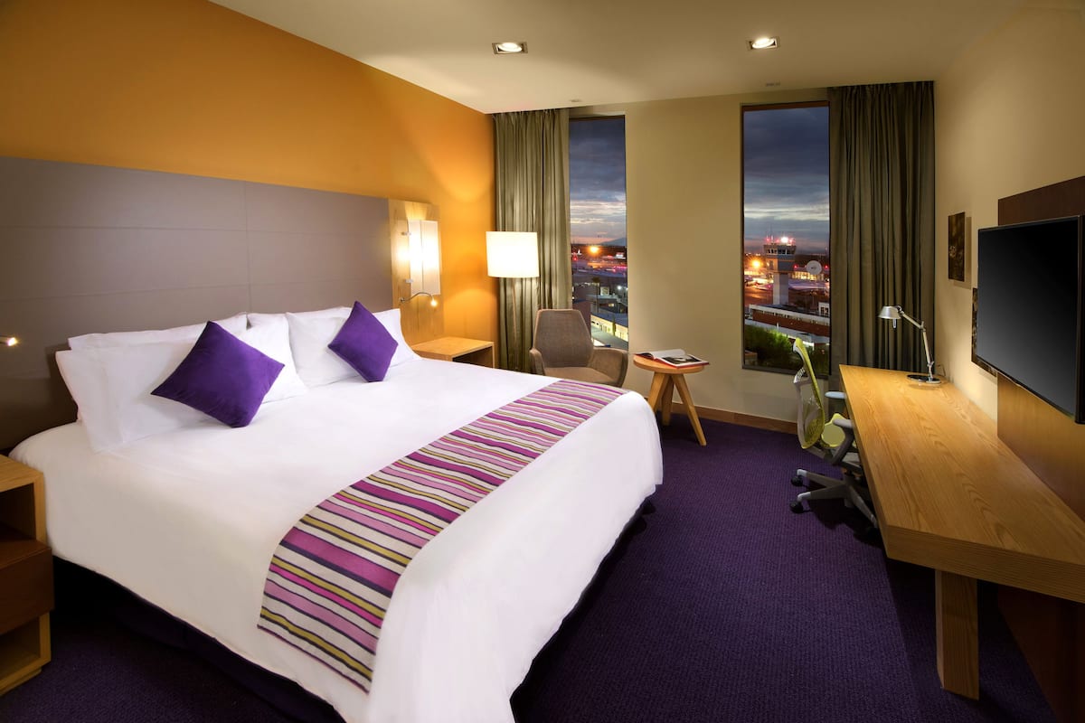Una habitación de hotel con una cama grande, un escritorio, una silla y un televisor.