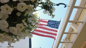 An American flag hanging on a balcony railing with white flowers in the foreground. - Four Jacks Hotel and Casino (Jackpot)