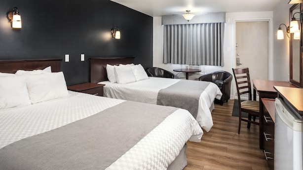 Een hotelkamer met twee bedden, een bureau, een stoel en een klein tafeltje.