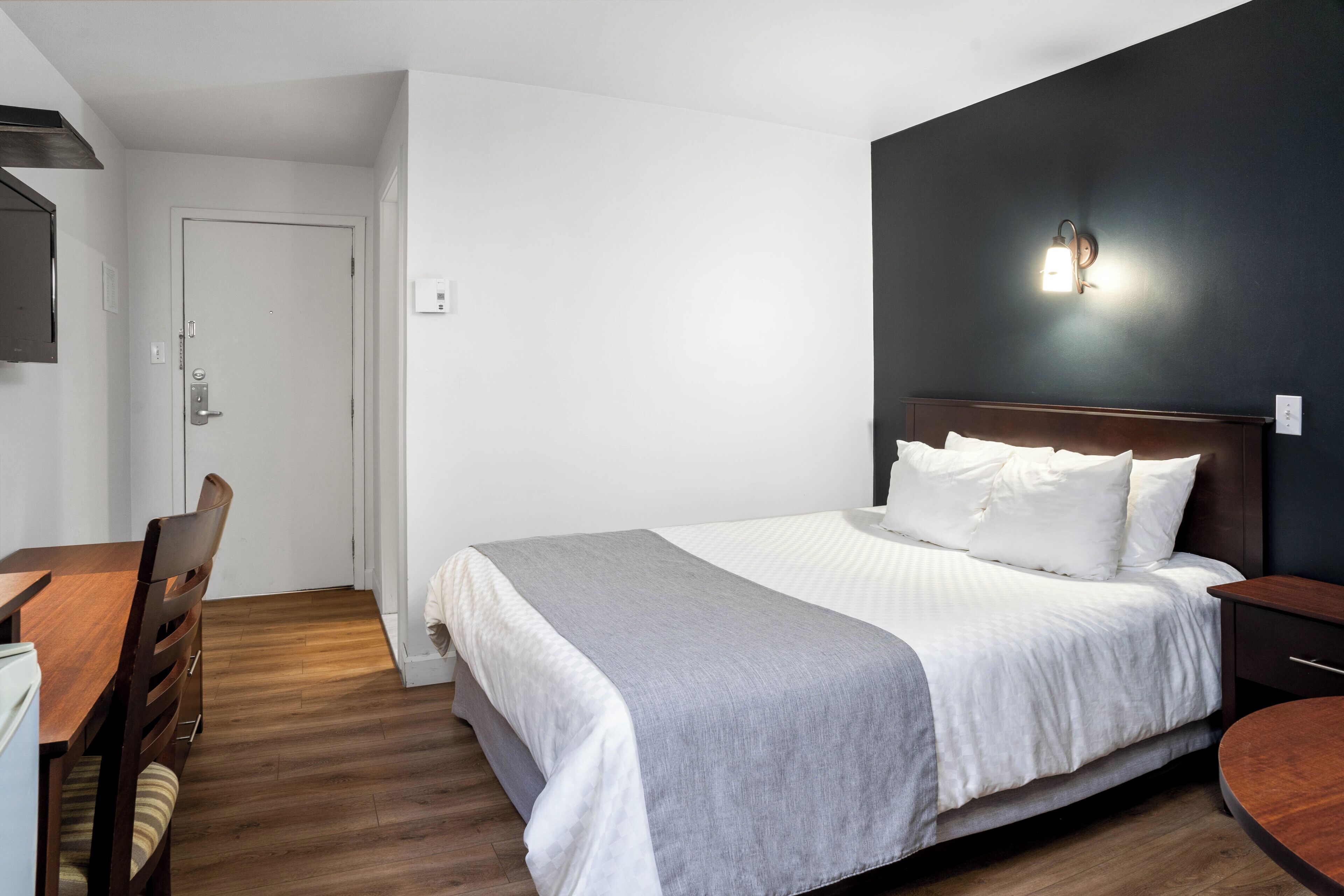 A bedroom with a bed, bedside table, and a desk with a chair.