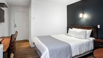 A bedroom with a bed, bedside table, and a desk with a chair.
