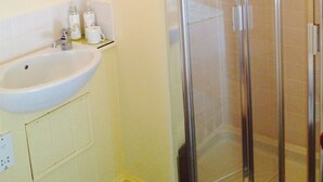 A bathroom with a white sink, a mirror, and a glass shower enclosure. - April Cottage (York)