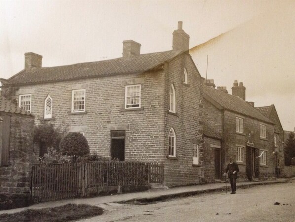 A stone building with a gabled roof and multiple windows. - April Cottage (York)
