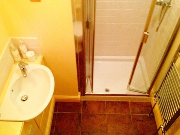A bathroom with a sink, a glass shower enclosure, and a tiled floor. - April Cottage (York)