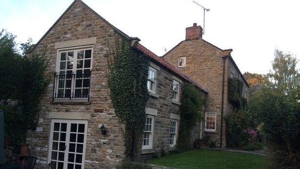 A stone house with a large front door and a small balcony. - April Cottage (York)