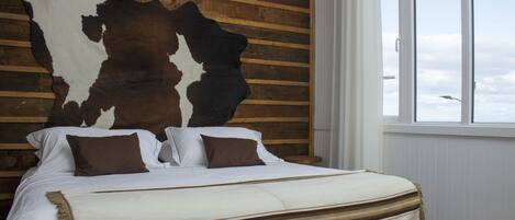 Een bed met een gestreept dekbed, kussens en een groot dierenhuid aan de muur.