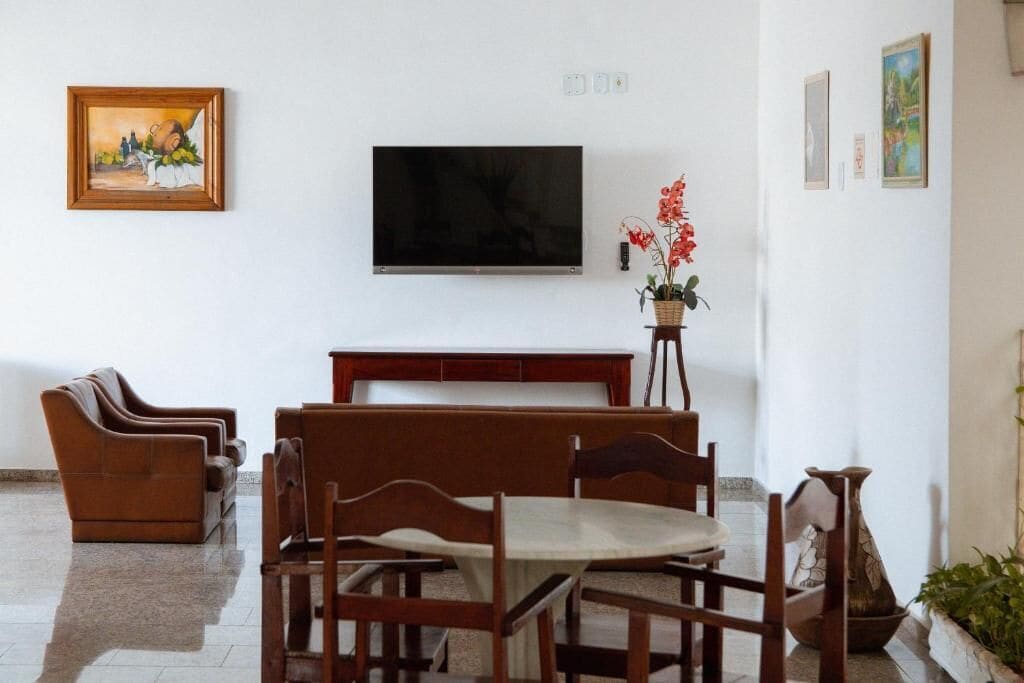 Un área de comedor con una mesa y sillas de madera, un sofá y un televisor montado en la pared.