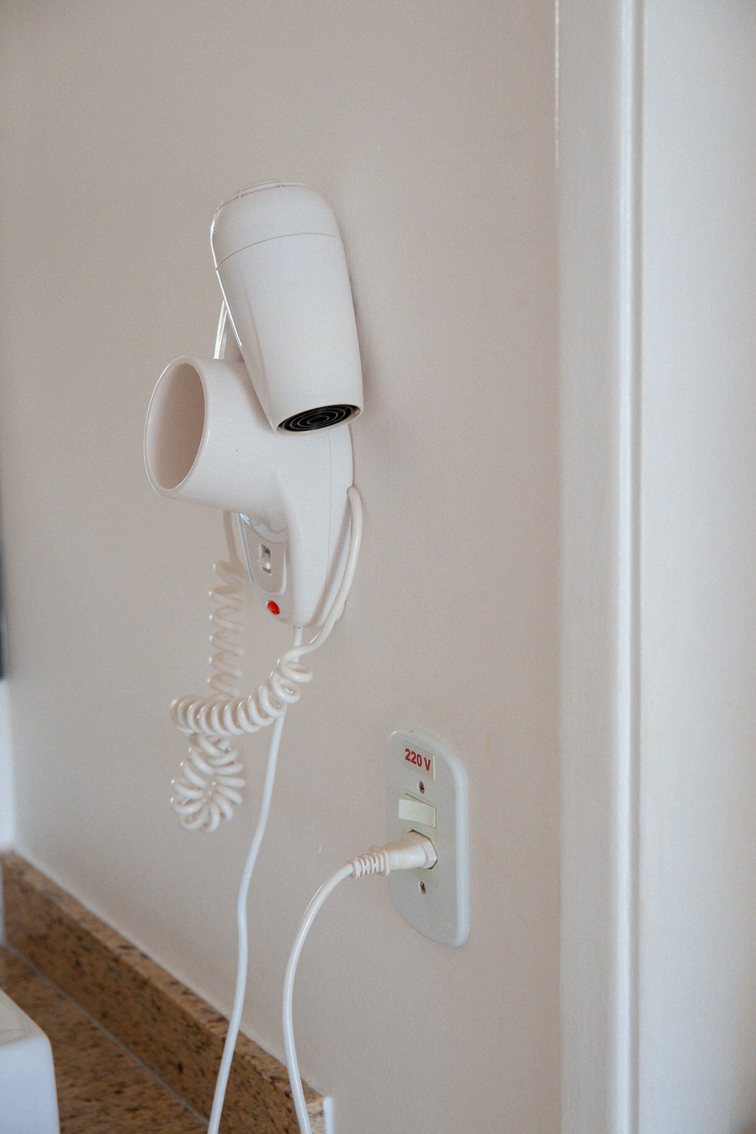 Een haardroger bevestigd aan een muur met een stopcontact.