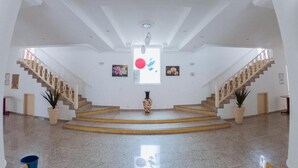 A spacious lobby with a central staircase, a large artwork on the wall, and potted plants. - Hotel Recanto dos Pássaros (São Sebastião)