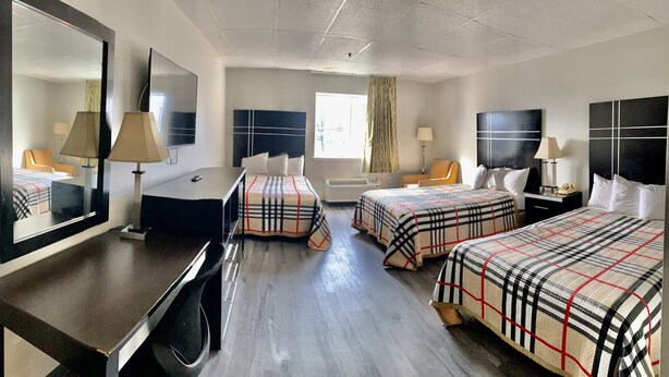 Une chambre d’hôtel avec deux lits, un bureau, une télévision et un miroir.