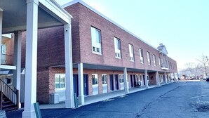 Un immeuble de plusieurs étages, construit en briques, doté d’une entrée couverte et d’un parking situé à l’avant.
