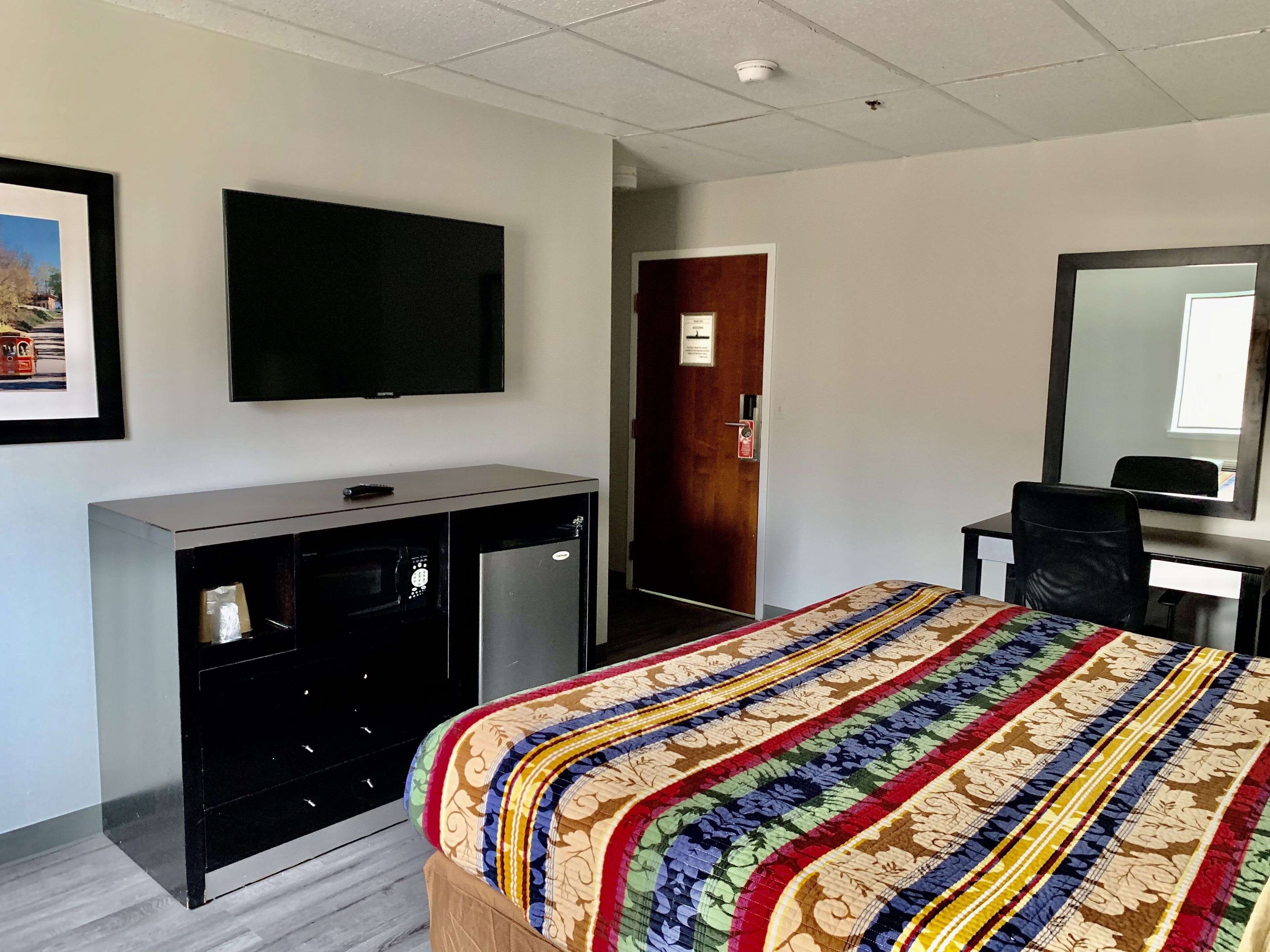 A hotel room with a bed, a desk, a television, and a wardrobe.