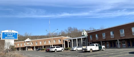 A Tappan Zee Hotel with a parking lot, brick buildings, and a clear sky.