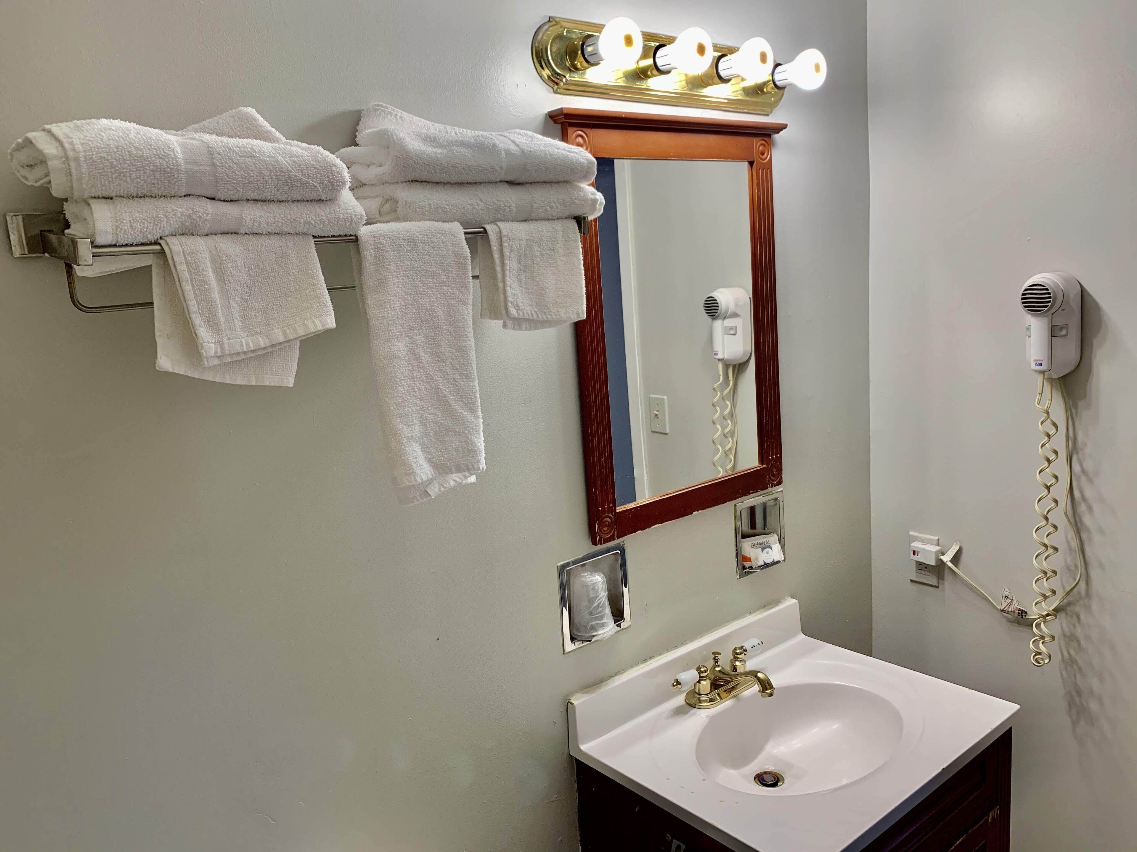 A bathroom with a sink, mirror, towel rack, and hair dryer.