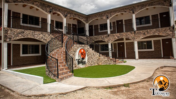 A multi-story building with a central staircase, stone facade, and multiple balconies. - Hotel Taramuri (Bocoyna)