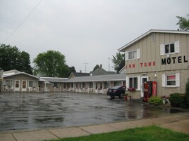 Um motel com estrutura em dois andares, uma máquina de refrigerantes Coca-Cola e um carro estacionado na frente.