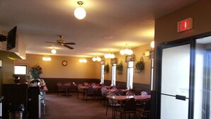A restaurant with multiple tables and chairs, ceiling fans, and wall-mounted lights. - Best Seven Inn (Claresholm)