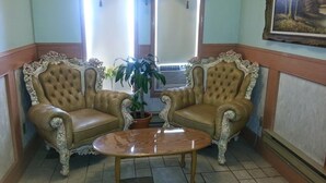A room with two ornate leather armchairs facing each other, a small round table, and a potted plant between them. - Best Seven Inn (Claresholm)