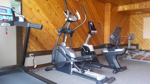A gym with treadmills, elliptical machines, and a rowing machine. - Best Seven Inn (Claresholm)