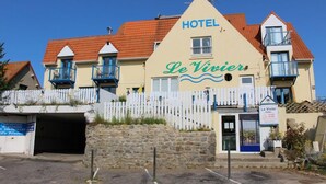 A hotel named Le Vivier with a white facade, red roof, and blue balconies.