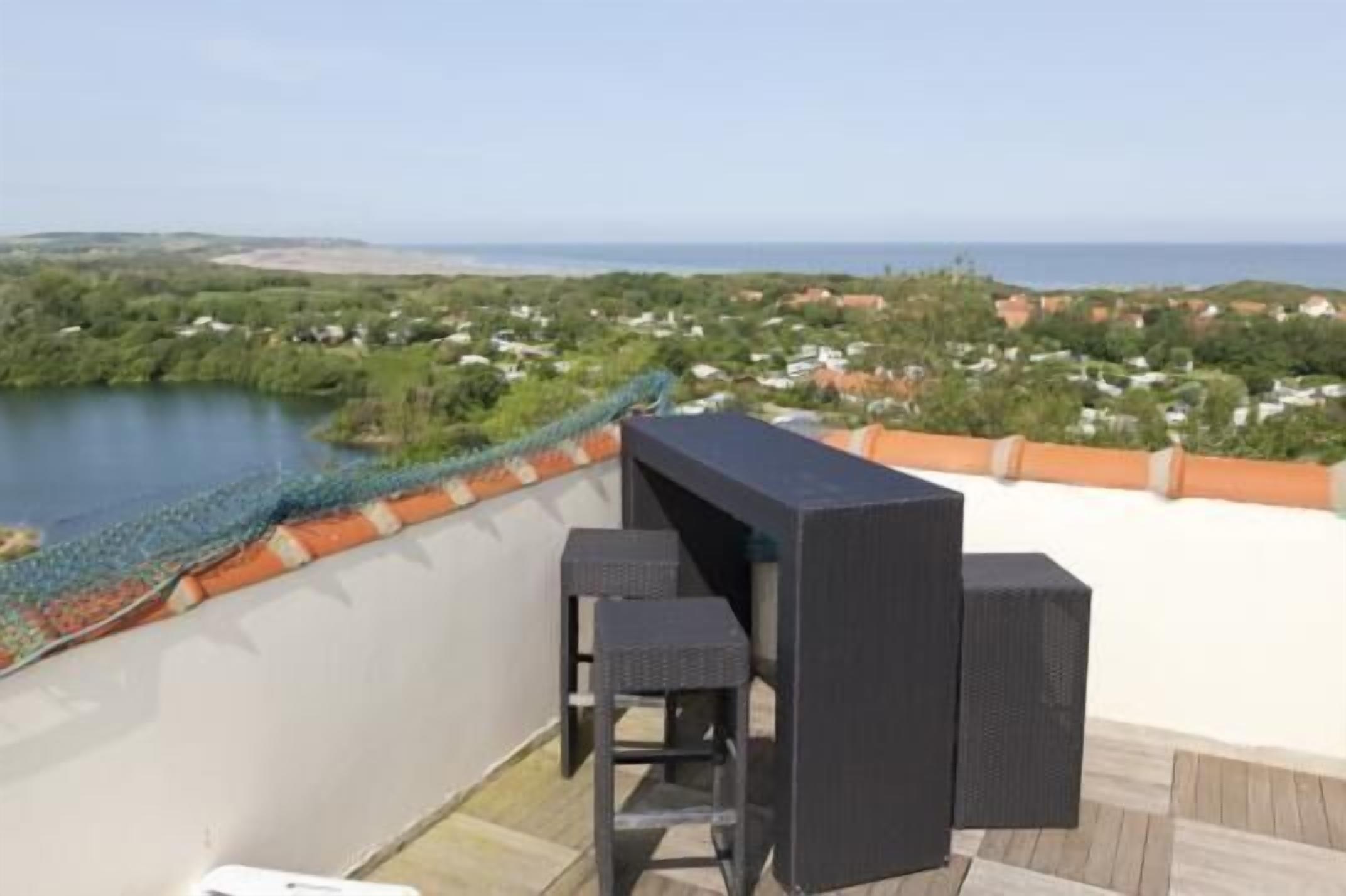 A rooftop terrace with a view of a lake and distant landscape.