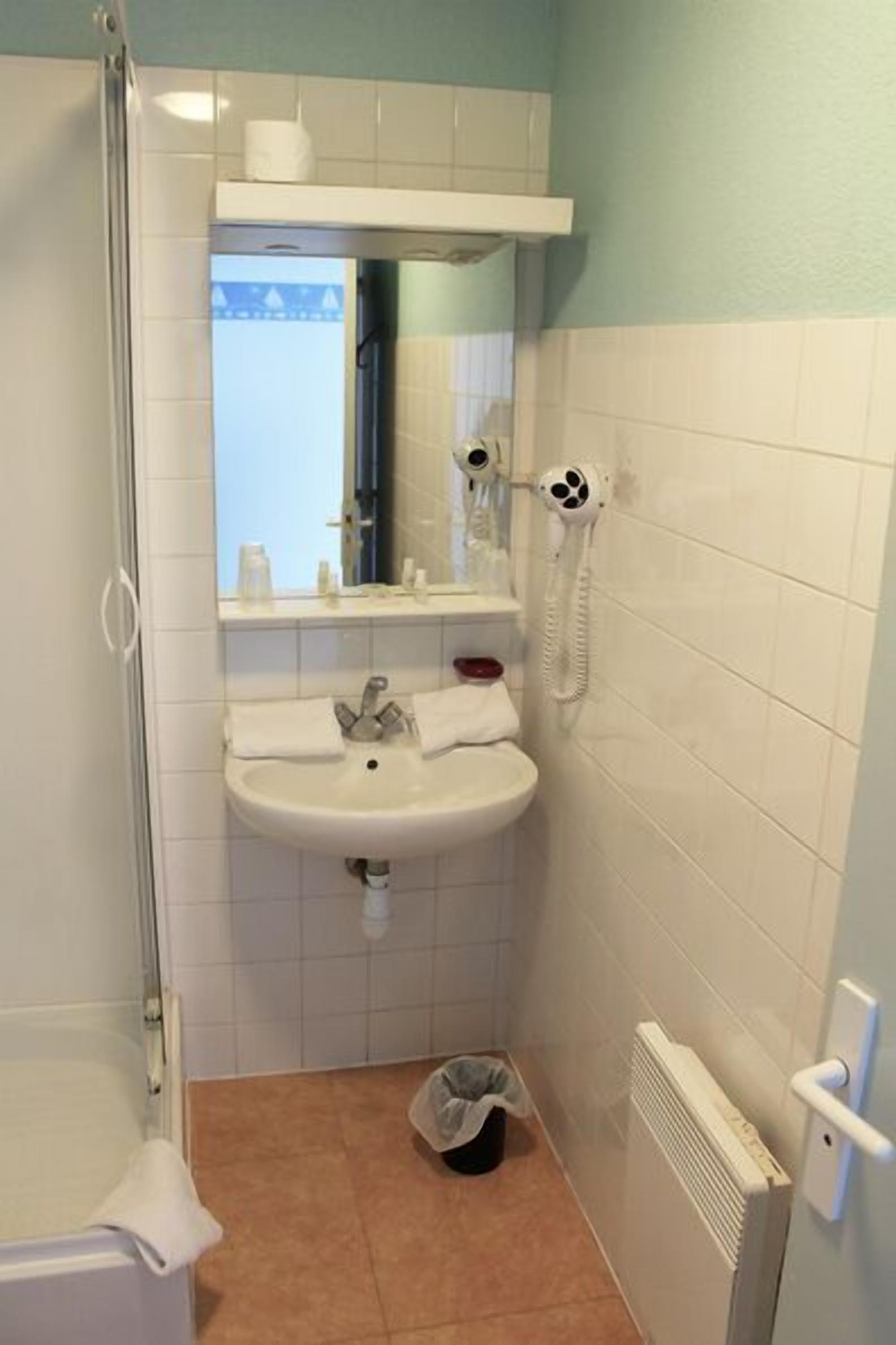 A bathroom with a white sink, mirror, and a hairdryer on the wall.