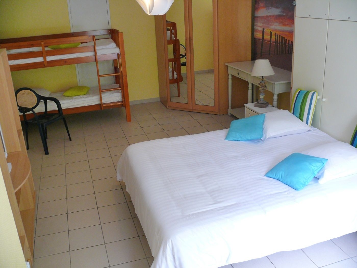 Una habitación con una cama individual doble, un escritorio con lámpara, una silla y una cama con almohadas.