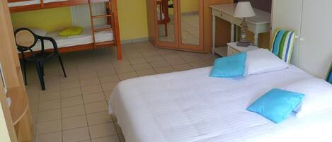 Una habitación con una cama individual doble, un escritorio con lámpara, una silla y una cama con almohadas.