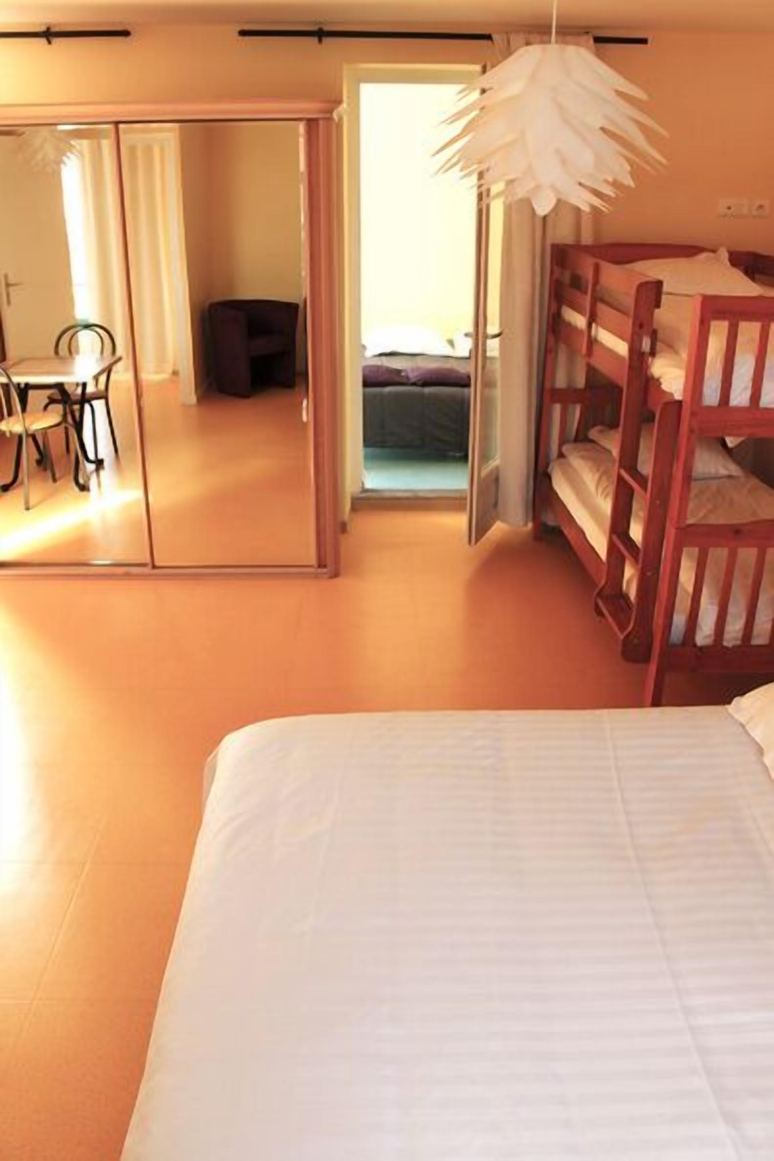 A bedroom with a bunk bed, a desk with a chair, a mirror, and a hanging light fixture.