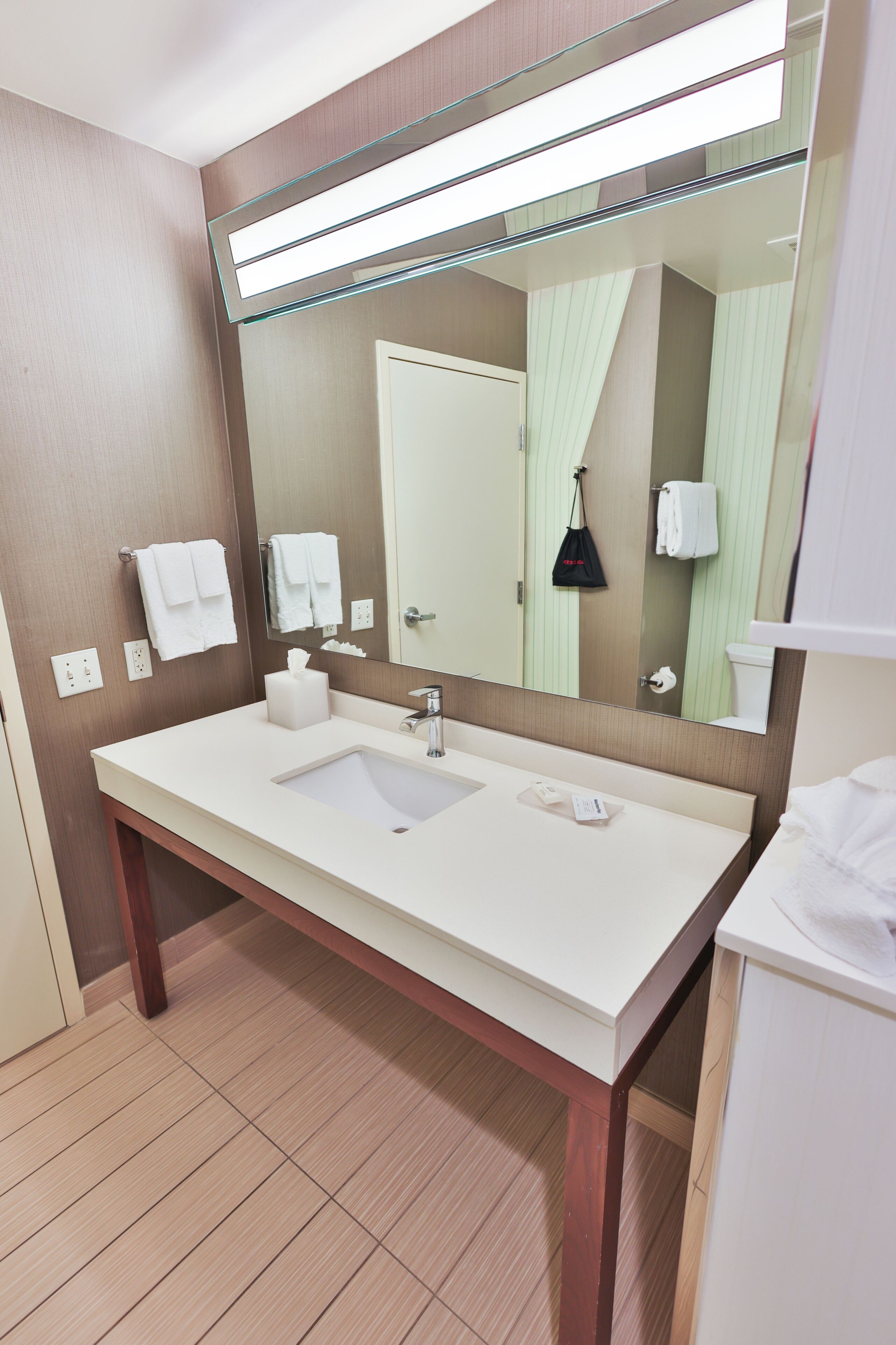 Une salle de bain moderne avec un grand miroir, un lavabo blanc et un porte-serviettes.
